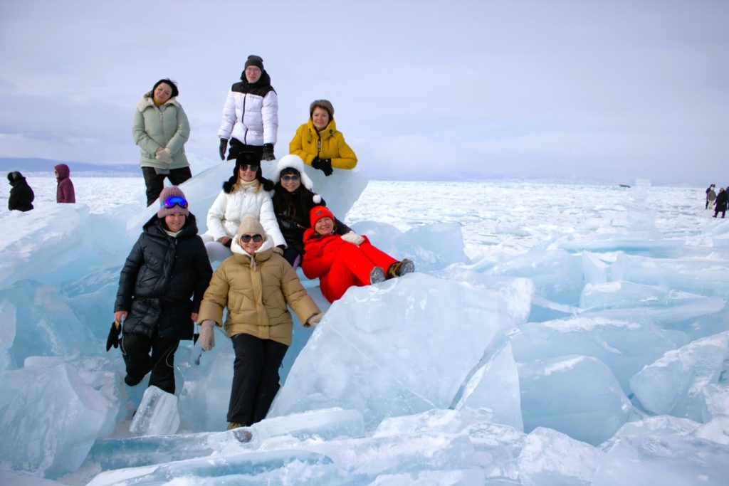 люди фотографируются зимой на байкале среди кусков льда