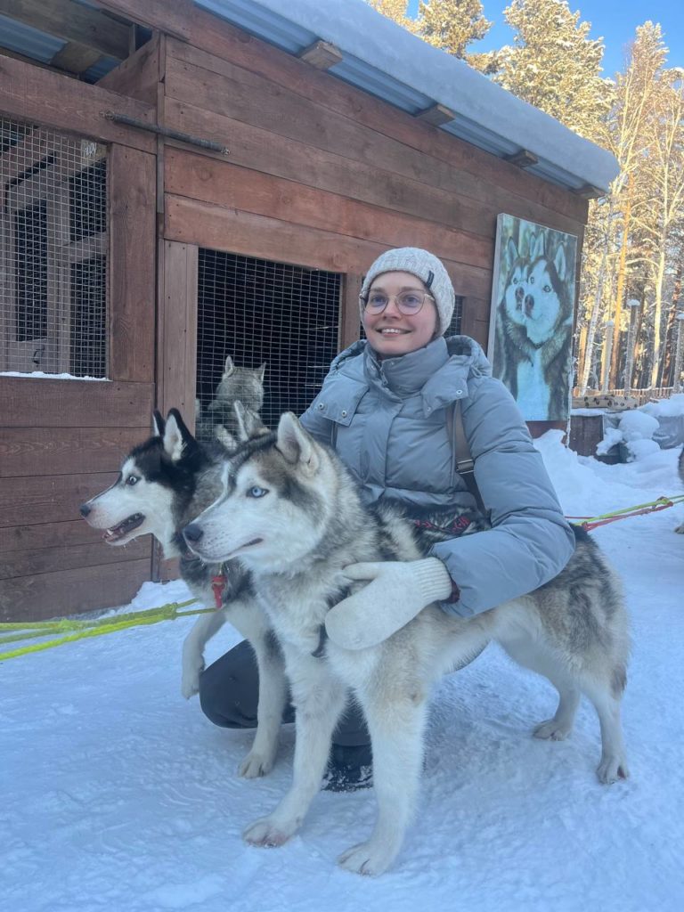 Девушка обнимает двух собак породы хаски на Байкале