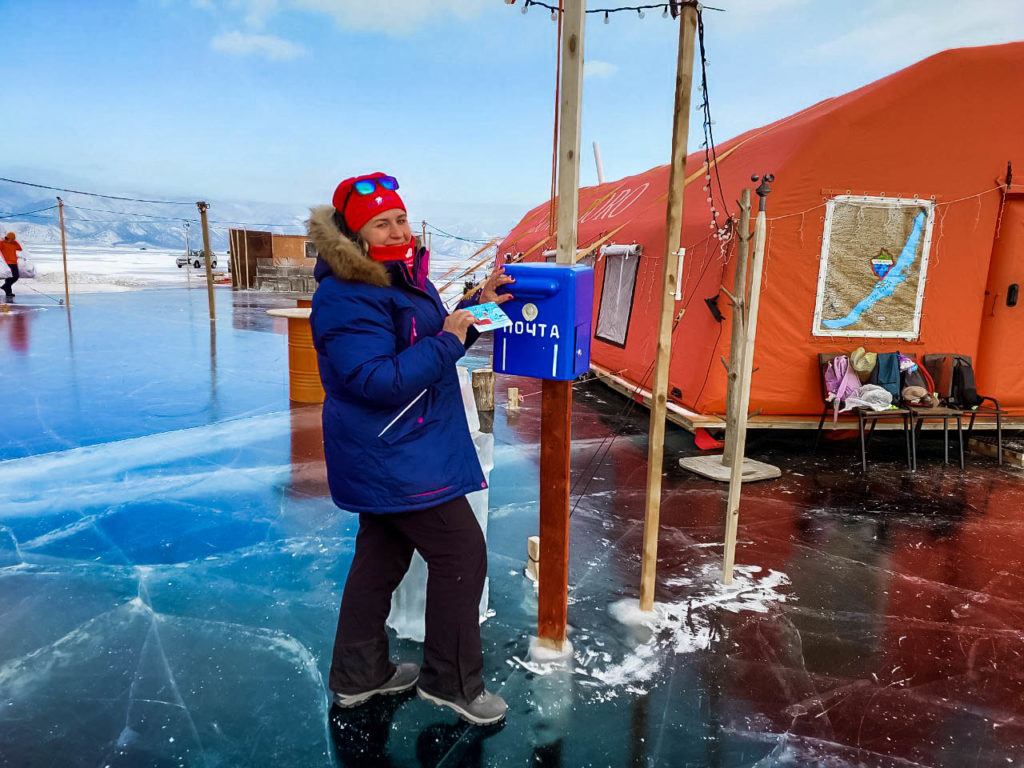 Женщина кладет письмо в почтовый ящик прямо на льду на Байкале