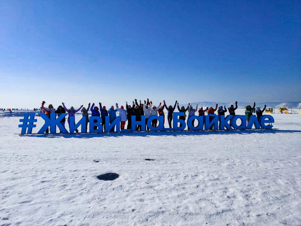 Люди стоят за надписью: живи на Байкале